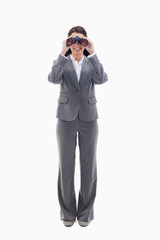 Businesswoman smiling and looking through binoculars
