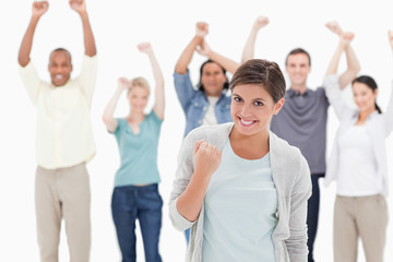 Obraz premium Woman clenching her fist with people behind raising their arms