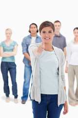 Obraz premium Close-up of a woman giving the thumb-up with people behind