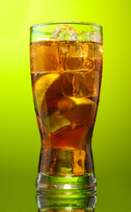 Iced tea with lemon and lime on green background