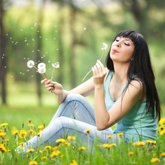 Cute woman in the park with dandelions