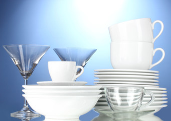 empty bowls, plates, cups and glasses on blue background