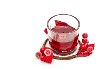 Red berry wreath around a lit red candle on a white background