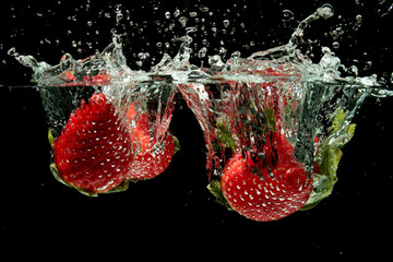 Strawberries splashing into water