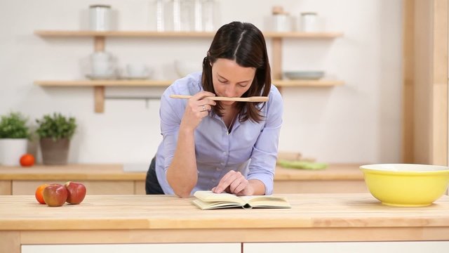 l&auml;chelnde frau liest im kochbuch