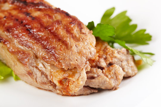 Grilled meat on white plate closeup