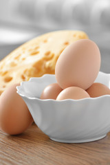 Chicken eggs in white dish with cheese on a wooden table