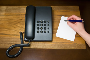 landline telephone and human hand writing note