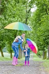 mother and her daughter with umbrellas in spring alley