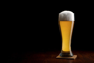 Beer into glass on a black and wooden table