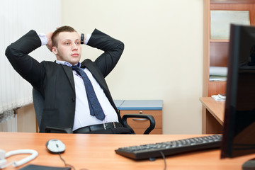 Relaxed businessman sitting at desk, thinking about something