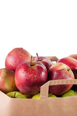 Fresh red apples in a paper shopping bag, white background