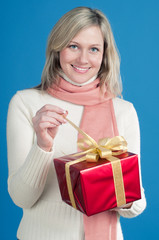 Young blond hair woman opening a gift box wrapped with gold bow