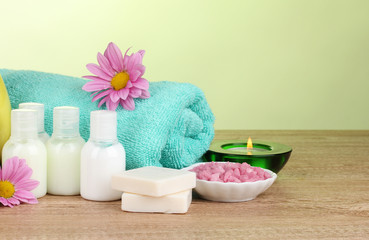 Hotel amenities kit on wooden table on green background