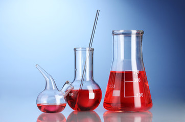 Three flasks with red liquid with reflection on blue background