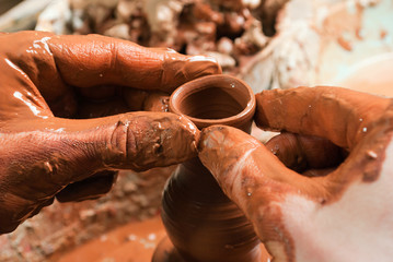 hands of a potter, creating an earthen jar on the circle