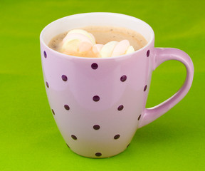 Cup of cappucino with marshmallows on green background