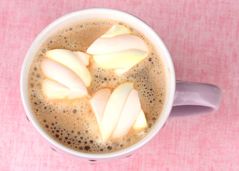 Cup of cappucino with marshmallows on pink background