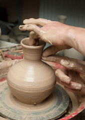 hands of a potter, creating an earthen jar on the circle