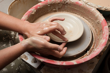 hands of a potter, creating an earthen jar on the circle