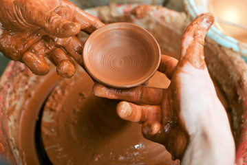 hands of a potter, creating an earthen jar on the circle