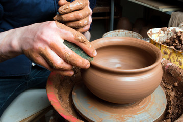 hands of a potter, creating an earthen jar on the circle