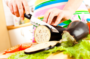 Woman's hands cutting aubergine eggplant