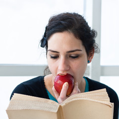 Portrait of a student eating an apple while reading