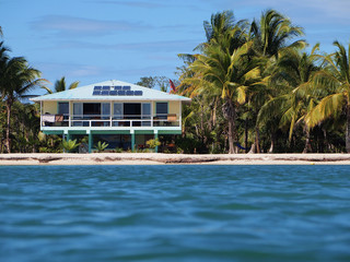 Beach house with solar panels on a tropical beach seen from water surface, Caribbean sea