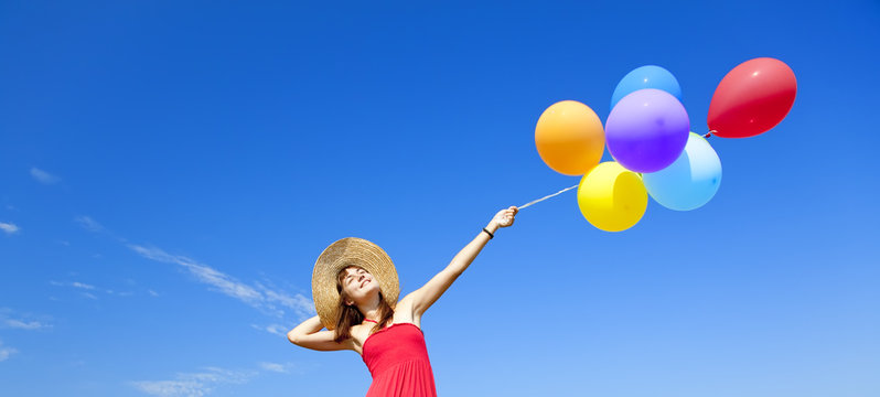 Brunette girl with colour balloons at blue sky background.