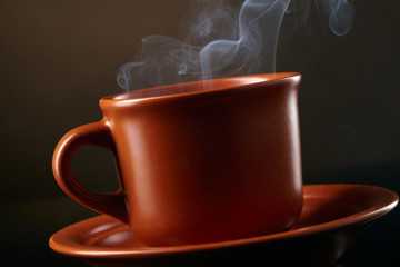 Cup of coffee with smoke over dark backgroun