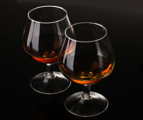 Two glasses of cognac on black background