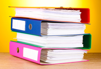 bright office folders on wooden table on yellow background.