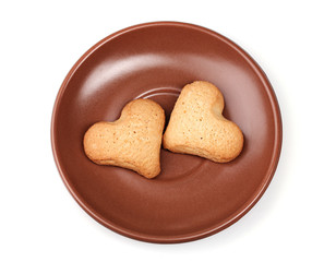 Two heart-shaped cookies on brown saucer isolated on white