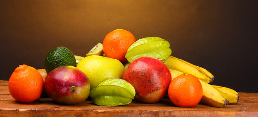 Assortment of exotic fruits on wooden table on brown background