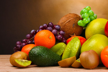 Assortment of exotic fruits on wooden table on brown background