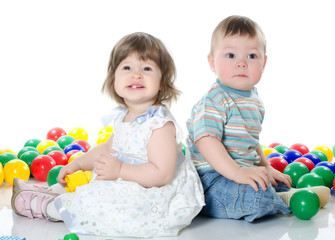 Obraz premium The little girl and boy plays multi-coloured balls isolated