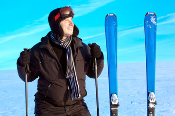 Young smiling skier guy standing in winter mountain landscape