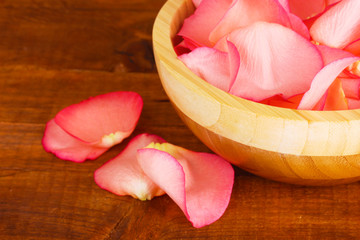 beautiful pink rose petals in wooden bowl on table