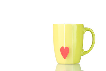Green cup and tea bag with red heart-shaped label isolated