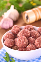 Raw meatballs with garlic in a white bowl (Selective Focus)