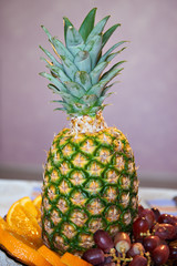 Pineapple with slices of oranges and grapes