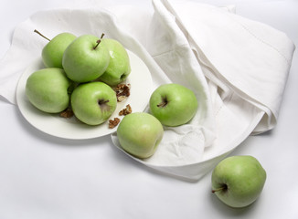 Green apples on a porcelain plate with linen