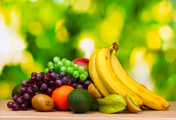Naklejka na ściany i meble Assortment of exotic fruits on wooden table on green background