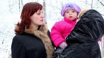 Two females talks in park, one holds kid on hands