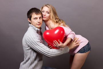 Portrait of two young people holding heart-shaped balloon