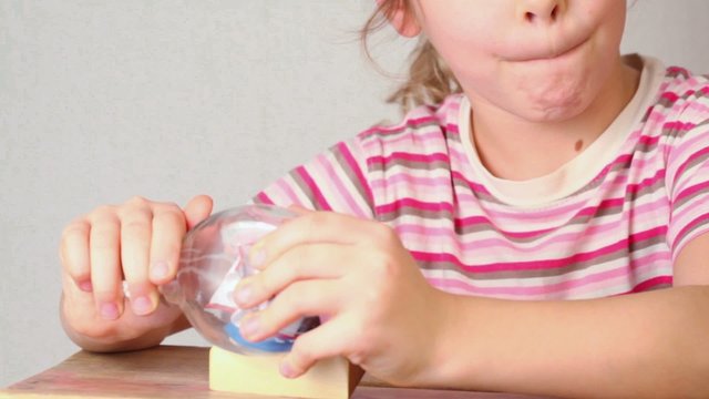 Girl looks at model of tallship in glass bottle stand on table