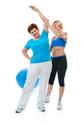 Senior woman doing fitness exercise with help of trainer in gym