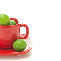green plum  in the red cup isolated on white