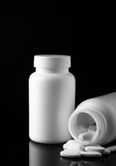 bottle with white pills on black background